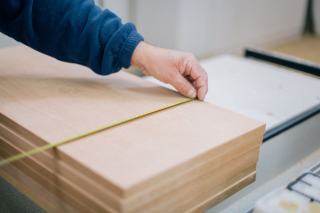 Mesure d'une pile de panneaux de bois au mètre ruban