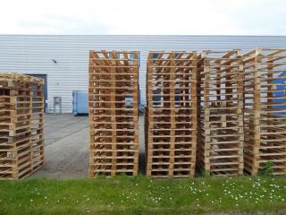 Piles de palettes en bois devant un bâtiment logistique